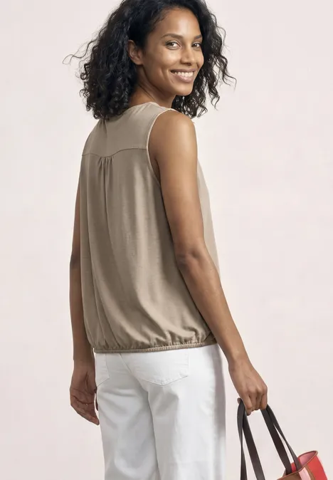 Top aus Jersey mit Elastiksaum sepia sand Frau von hinten in beigem Top, weißen Hosen, hält eine Handtasche in der Hand.