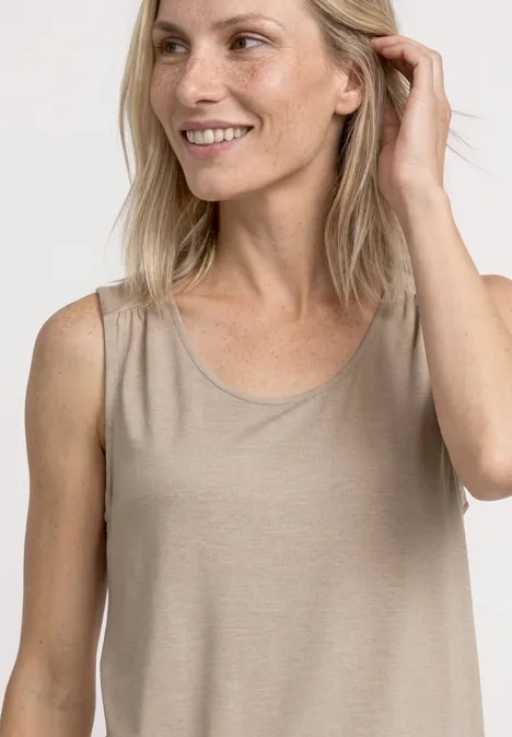 Top aus Jersey mit Elastiksaum sepia sand Eine lächelnde Frau in ärmellosem, beigem Top vor neutralem Hintergrund.