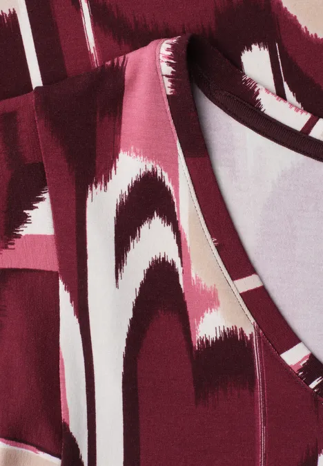 Close-up van een rood-wit abstract patroon op stof, waarschijnlijk kleding.