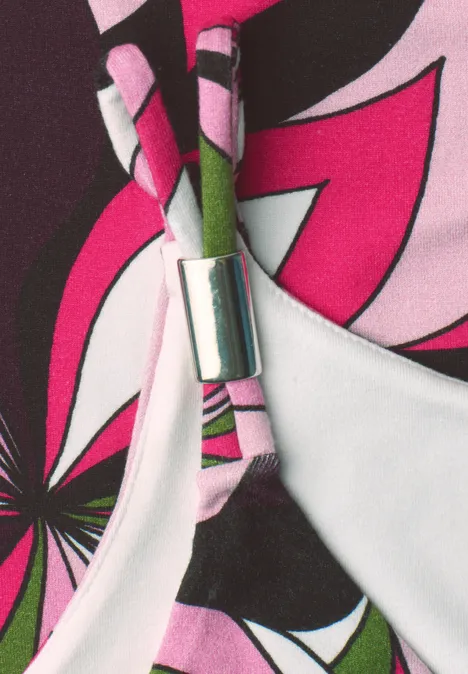 Gros plan d'un haut de bikini coloré à motif floral rose et noir avec attache métallique argentée.