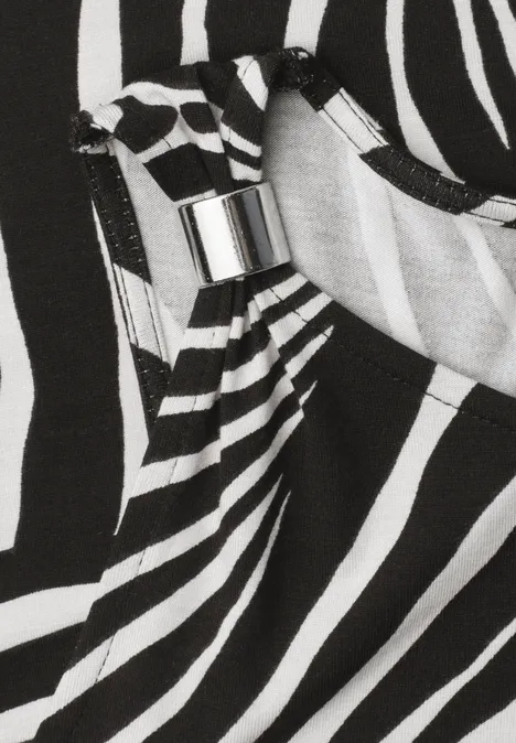 Close-up van een zwart-wit zebraprint stof met een zilverkleurige metalen gesp.