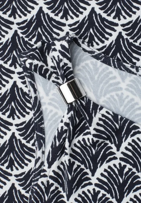 Tissu à motif éventail noir et blanc, maintenu par un anneau de serviette en argent.