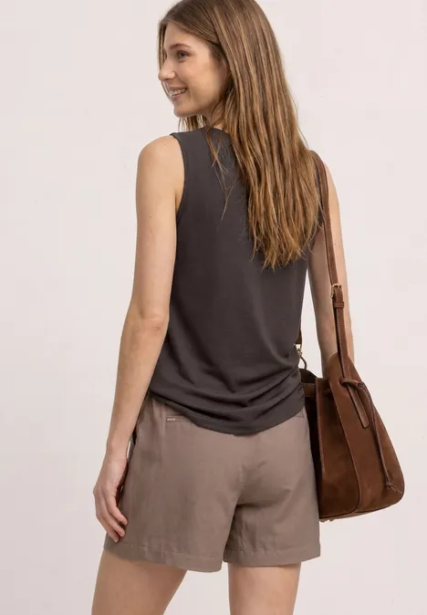 Frau von hinten in schwarzem ärmellosem Top, braunen Shorts und passender Handtasche.
