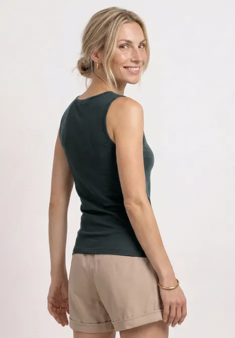 Eine Frau von hinten in schwarzem Top und beigen Shorts vor weißem Hintergrund.