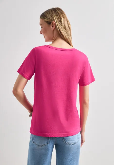 Frau von hinten mit pinkem T-Shirt und blauen Jeans.
