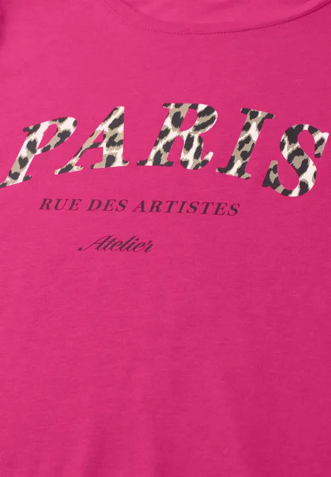 Ein pinkes Shirt mit gemustertem Schriftzug 'PARIS Rue des Artistes Atelier'.