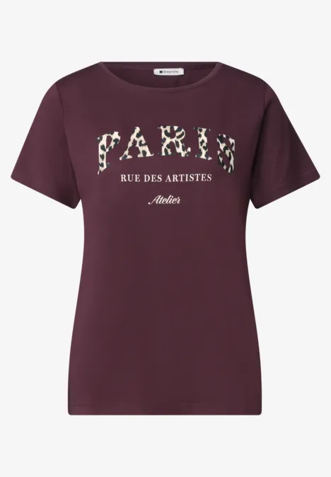 Ein bordeauxrotes T-Shirt mit Aufdruck 'PARIS RUE DES ARTISTES' in floralen Buchstaben.