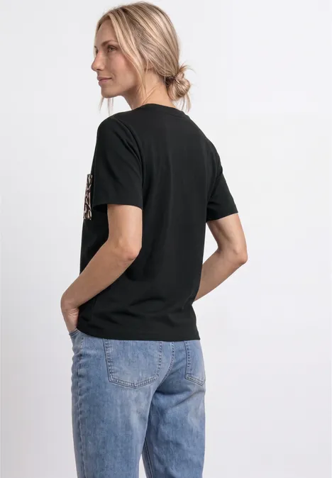 Femme de dos portant un t-shirt noir et un jean bleu.