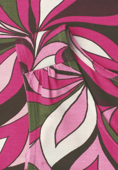 Buntes abstraktes Muster aus geschwungenen Blattformen in Pink, Weiß, Olivgrün und Schwarz.