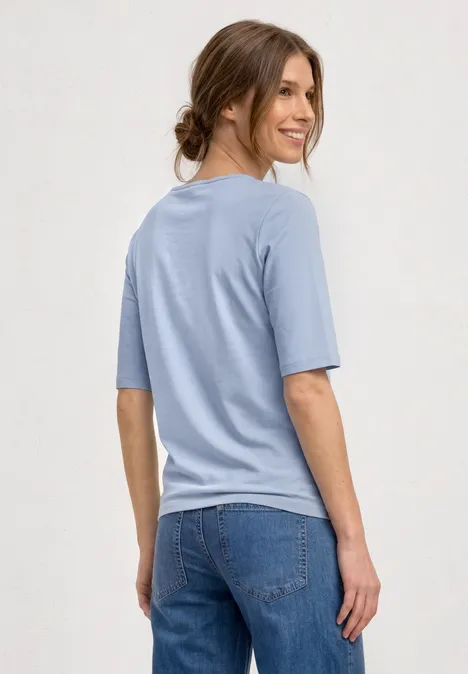 Frau von hinten in hellblauem T-Shirt und Jeans.