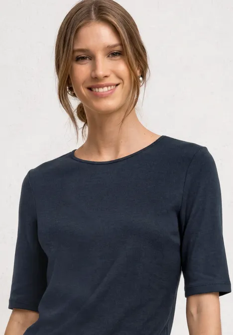 Frau mit einem dunkelblauen T-Shirt mit halblangen Ärmeln und Rundhalsausschnitt.