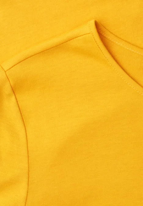 Nahaufnahme eines gelben T-Shirts mit erkennbarer Naht am Ärmel und Halsausschnitt.