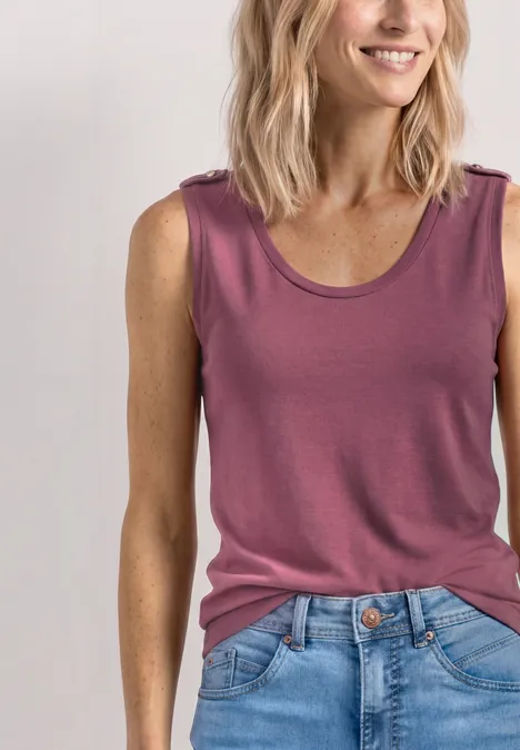 Femme en haut sans manches rose et jean bleu sur fond blanc.