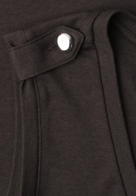 Haut à col en V et boutons black coffee Nahaufnahme eines schwarzen Kleidungsstücks mit aufgesetzter Tasche und sichtbarem Druckknopf