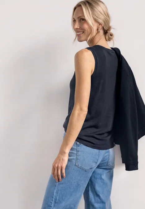 Haut à col V arrondi avec boutons aux épaules darkest blue Frau seitlich in ärmellosem schwarzen Top und Jeans, mit schwarzem Pullover über der Schulter.