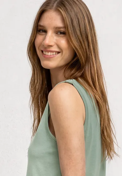 Top mit V-Neck und Knopfdetail eucalyptus green Seitliches Porträt einer jungen Frau mit langen braunen Haaren, die ein ärmelloses grünes Oberteil vor hellem Hintergrund trägt.