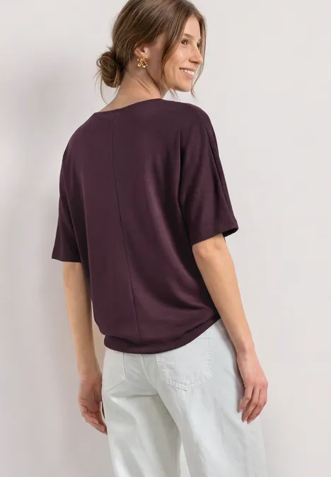 Basic Shirt met boothals en elastische zoom rustic rouge Vrouw van achteren gefotografeerd met een los donkerpaars shirt en lichte broek.