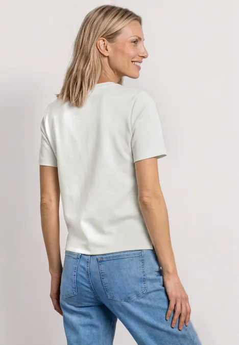 Shirt met decoratieve borstzak off white Vrouw van achteren met wit T-shirt en blauwe spijkerbroek voor neutrale achtergrond.
