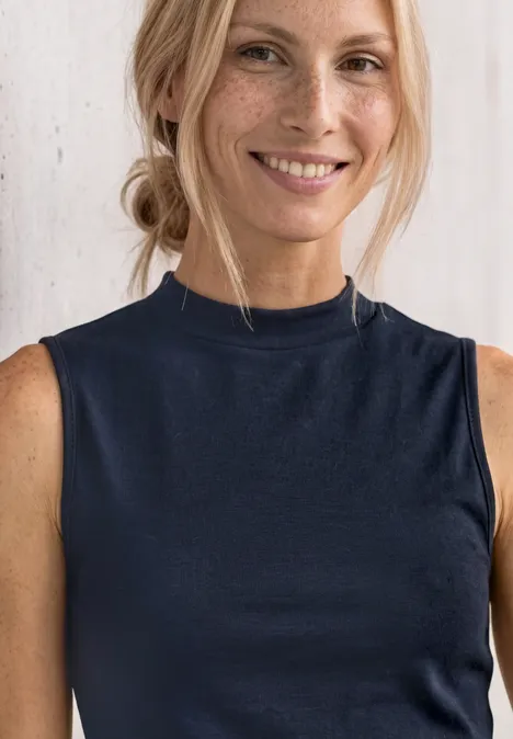 Silk-Look Top z golfem darkest blue Kobieta z blond włosami w koku nosi granatowy top bez rękawów z podwyższonym kołnierzem.