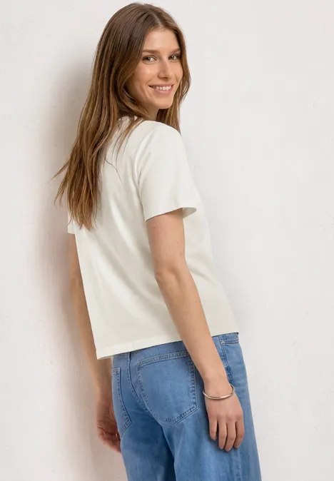 Femme de dos en t-shirt blanc et jean bleu, aux cheveux longs.