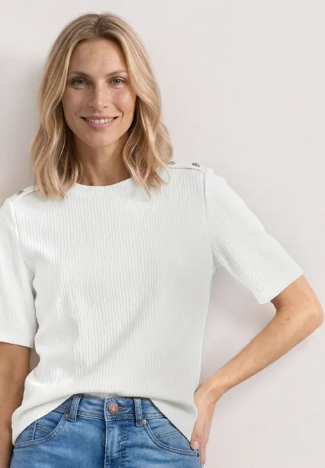 T-shirt à col rond avec boutons off white Femme aux cheveux blonds mi-longs en haut blanc à manches courtes côtelé et jean bleu.