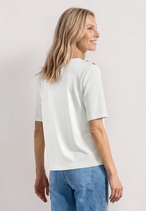 T-shirt à col rond avec boutons off white Femme vue de dos, T-shirt blanc et jean bleu, fond clair.