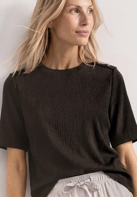 Frau in schwarzem, strukturiertem T-Shirt und grauer Hose