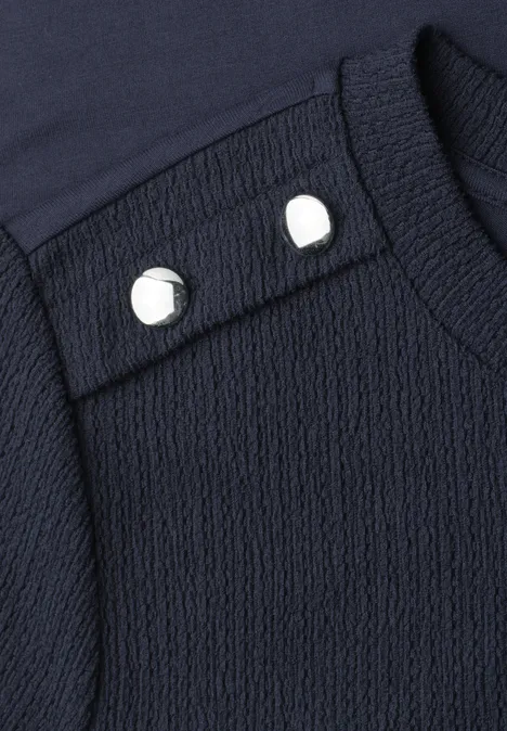 T-shirt à col rond avec boutons darkest blue Gros plan d'un vêtement bleu marine texturé avec deux boutons blancs sur l'épaule.