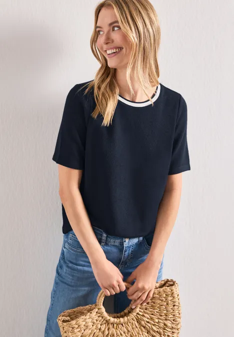 Shirt met gebreide look en ronde hals darkest blue Vrouw met donkerblauw t-shirt, spijkerbroek en geweven strooien tas voor lichte achtergrond.