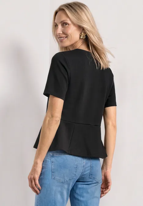 Frau von hinten in schwarzem, figurbetontem Shirt mit kurzen Ärmeln und Jeans.