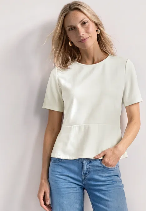 Shirt met ronde hals en volantdetail off white Vrouw met wit kort T-shirt en blauwe spijkerbroek tegen neutrale achtergrond.