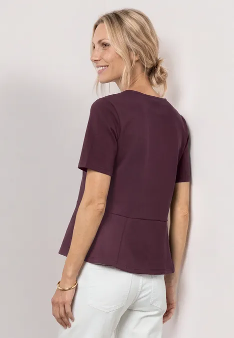 Shirt met ronde hals en volantdetail rustic rouge Vrouw van achteren met bordeauxrode top en witte broek, blond haar in losse knot