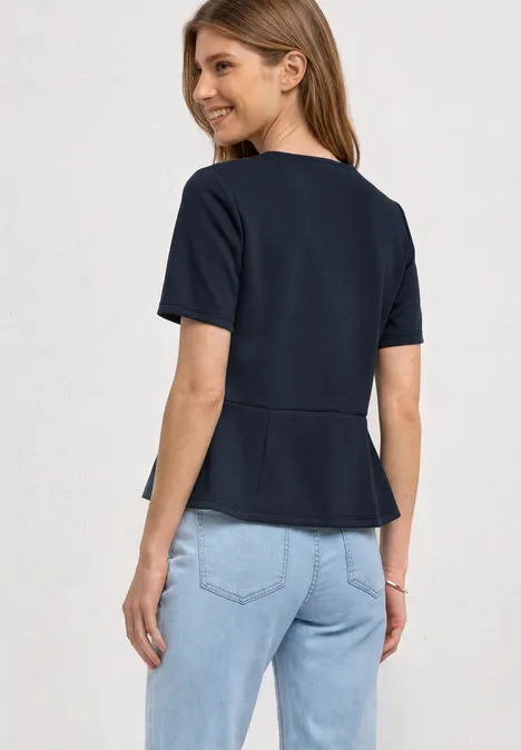 Shirt met ronde hals en volantdetail darkest blue Vrouw van achteren met donkerblauw T-shirt met korte mouwen en lichtblauwe jeans, kijkt om en lacht.
