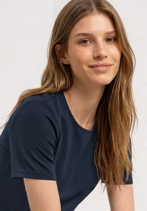 Shirt met ronde hals en volantdetail darkest blue Een persoon met lang blond haar draagt een donkerblauw T-shirt voor een lichte achtergrond.