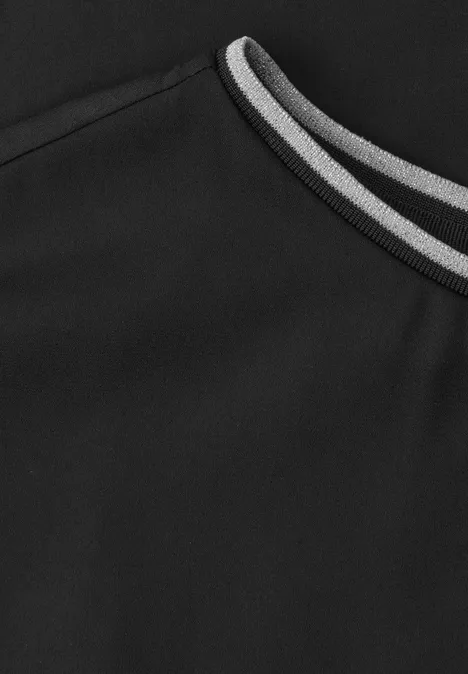 Gros plan sur un vêtement noir avec un détail de liseré gris et blanc à l'encolure