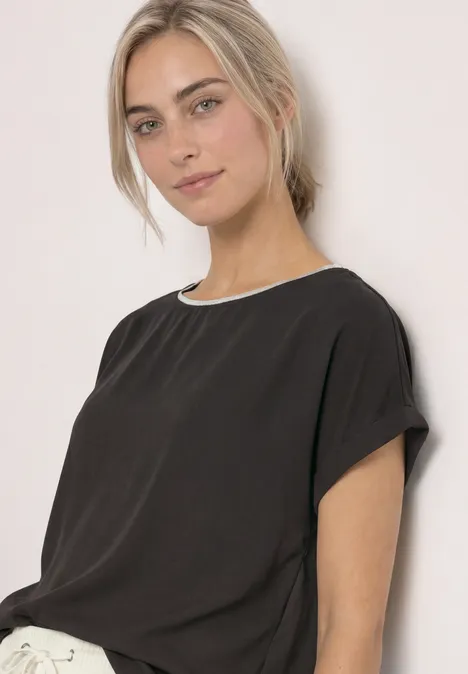 T-shirt 2 en 1 en chiffon, col bateau black coffee Jeune femme au teint clair portant un tee-shirt noir à manches courtes sur fond pâle.