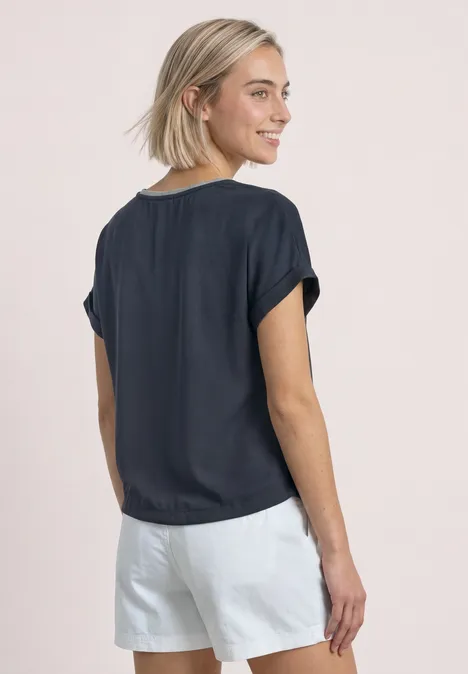 2-in-1 Shirt aus Chiffon mit Boat Neck darkest blue Frau mit kurzem blonden Haar trägt legeres dunkelblaues Shirt und weiße Shorts, seitlich von hinten.