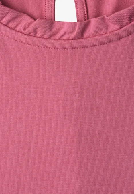 Nahaufnahme eines rosa Oberteils mit Rüschen am Halsausschnitt.