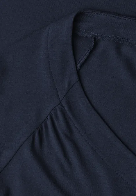Nahaufnahme eines dunkelblauen T-Shirt-Ausschnitts mit sichtbarer Naht und Falten im Stoff.