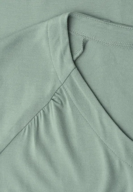 Nahaufnahme eines mintgrünen T-Shirts mit V-Ausschnitt und sichtbarer Naht.