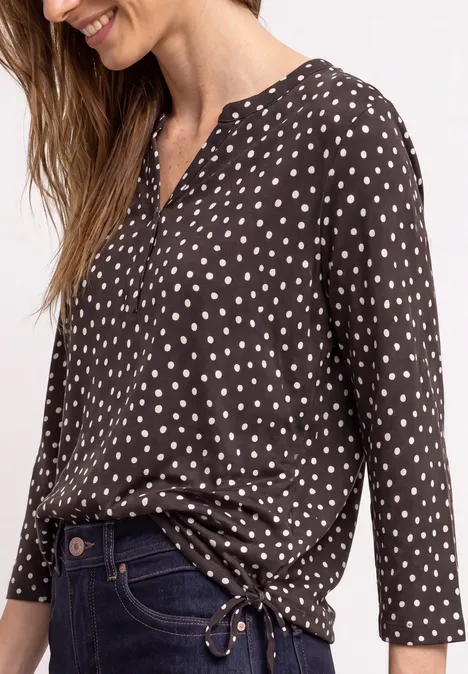 3/4-Arm Shirt mit Split Neck und Print black coffee Frau trägt schwarze Bluse mit weißen Punkten, langen Ärmeln und V-Ausschnitt, locker in Jeans gesteckt.