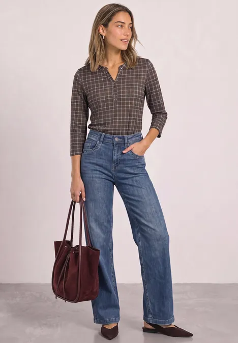 3/4-Arm Shirt mit Split Neck und Print silk brown Frau in kariertem Hemd, weiten Jeans und dunkler Tasche vor neutralem Hintergrund.