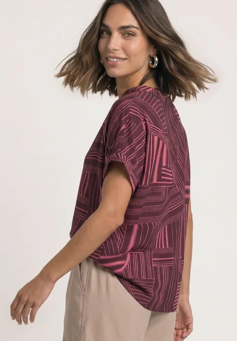 Dropped Shoulder Shirt mit Split Neck blush berry Eine Frau trägt ein kurzärmeliges, rot gemustertes Oberteil mit beige Hose.