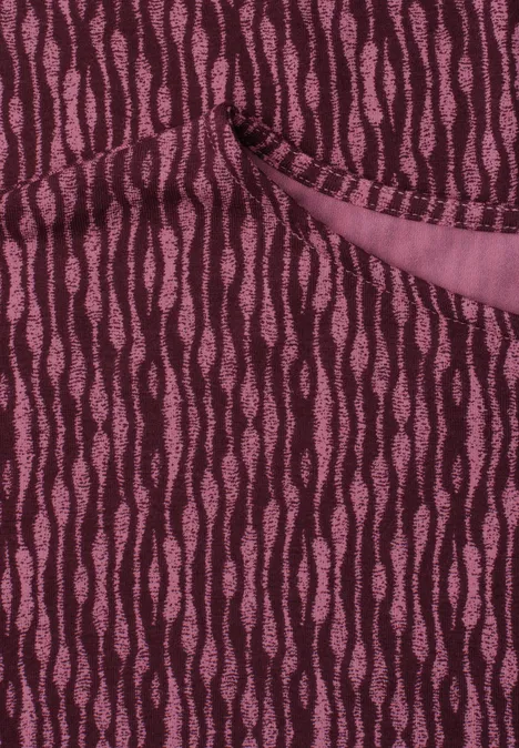 Nahaufnahme eines burgunderfarbenen Strickstoffs mit rosafarbenen, wellenförmigen Streifen und einer Tasche.