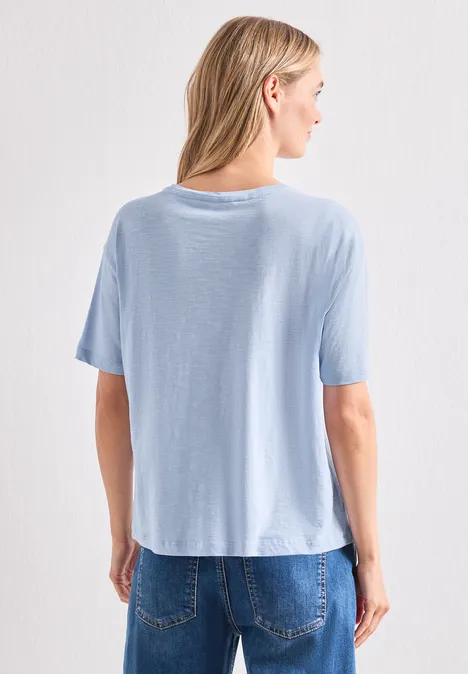 T-Shirt mit Rundhals und Frontprint whispery blue Rückansicht einer Frau in hellblauem T-Shirt und Jeans vor weißem Hintergrund.