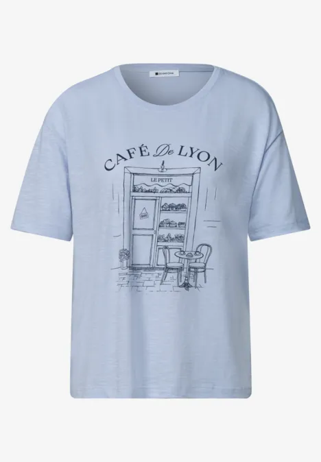 T-Shirt mit Rundhals und Frontprint whispery blue Hellblaues T-Shirt mit skizzenhaftem Café-de-Lyon-Motiv, Frontansicht mit Tisch und Stühlen.