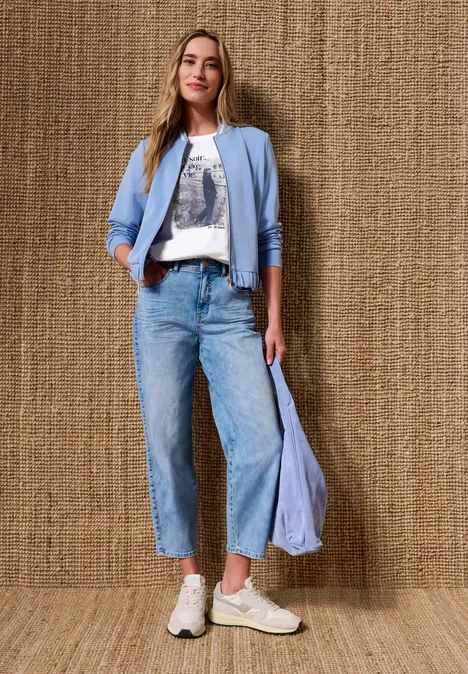 T-Shirt mit Rundhals und Fotoprint White Frau in Streetstyle-Look: T-Shirt mit Print, helle Bomberjacke, weitgeschnittene Jeans, weiße Sneaker.