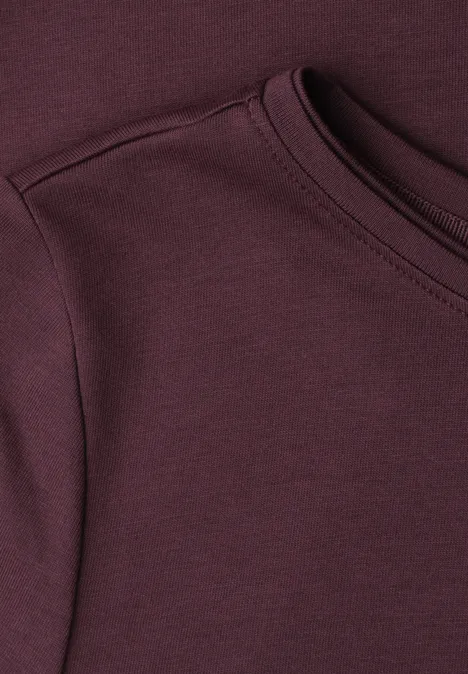 Nahaufnahme eines dunkelroten T-Shirts mit Rundhalsausschnitt und angesetztem Ärmel.