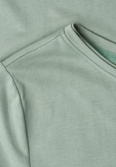 Nahaufnahme eines hellgrünen T-Shirts mit Rundhalsausschnitt und Schulternaht.