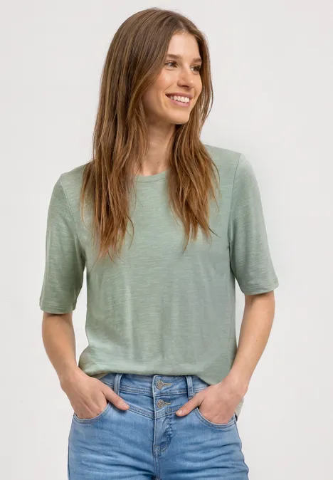 Basic Shirt met ronde hals in Unifarbe eucalyptus green Vrouw met vervaagd gezicht draagt groen t-shirt en jeans, handen in de zakken